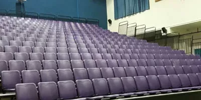Retractable bleachers with purple seats in Abu Dhabi indoor sports facility, telescopic seating for multi-purpose events