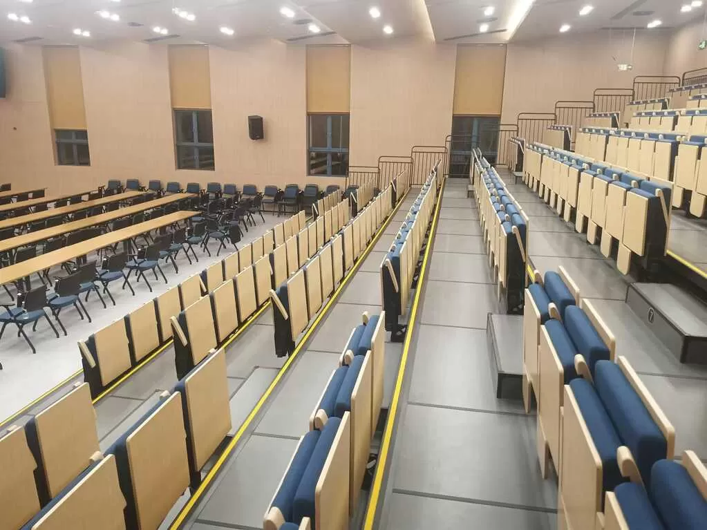 Extended retractable seating telescopic tribune SOLU soft seats with armrests writing tablets university auditorium